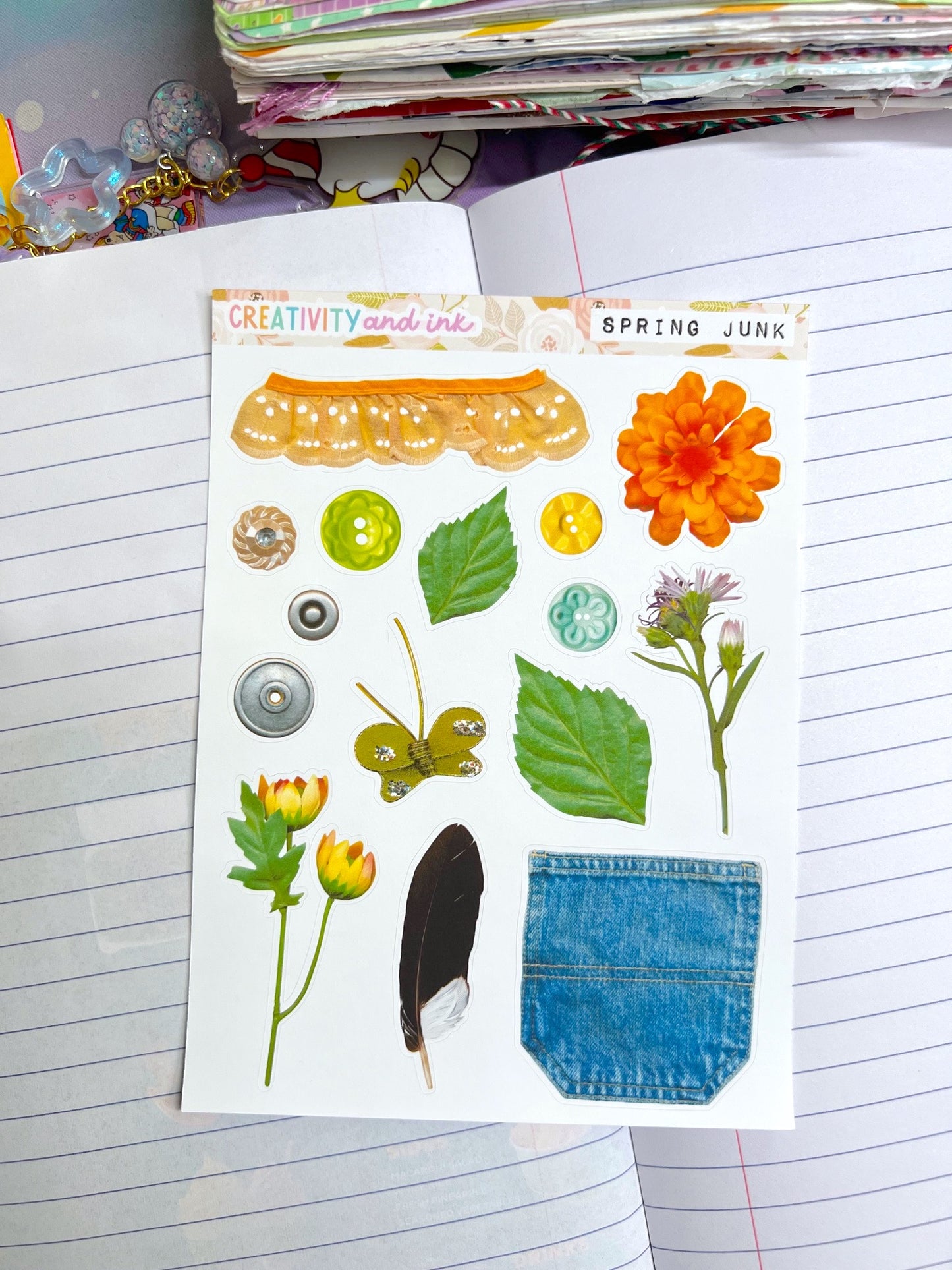 a mix of items including flowers buttons and more as a sticker sheet on top of a notebook background