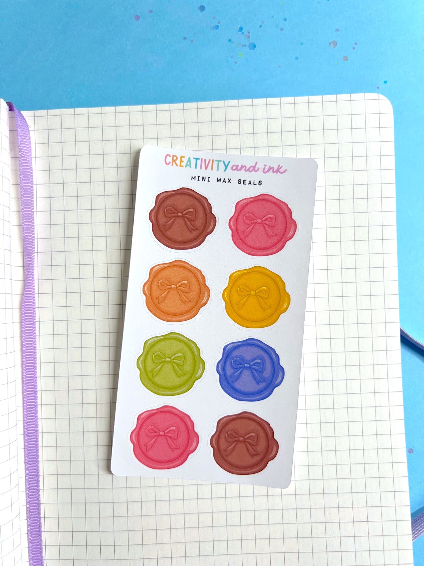 Sheet of colorful wax seal stickers on a notebook with a blue background