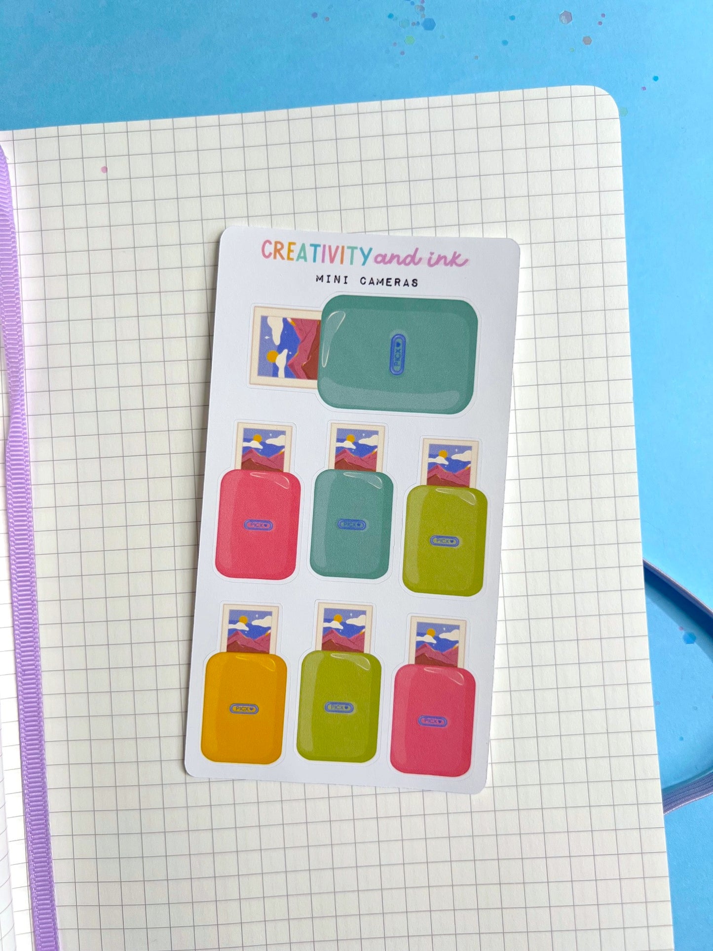 mini cameras as stickers on a sticker sheet on a notebook background