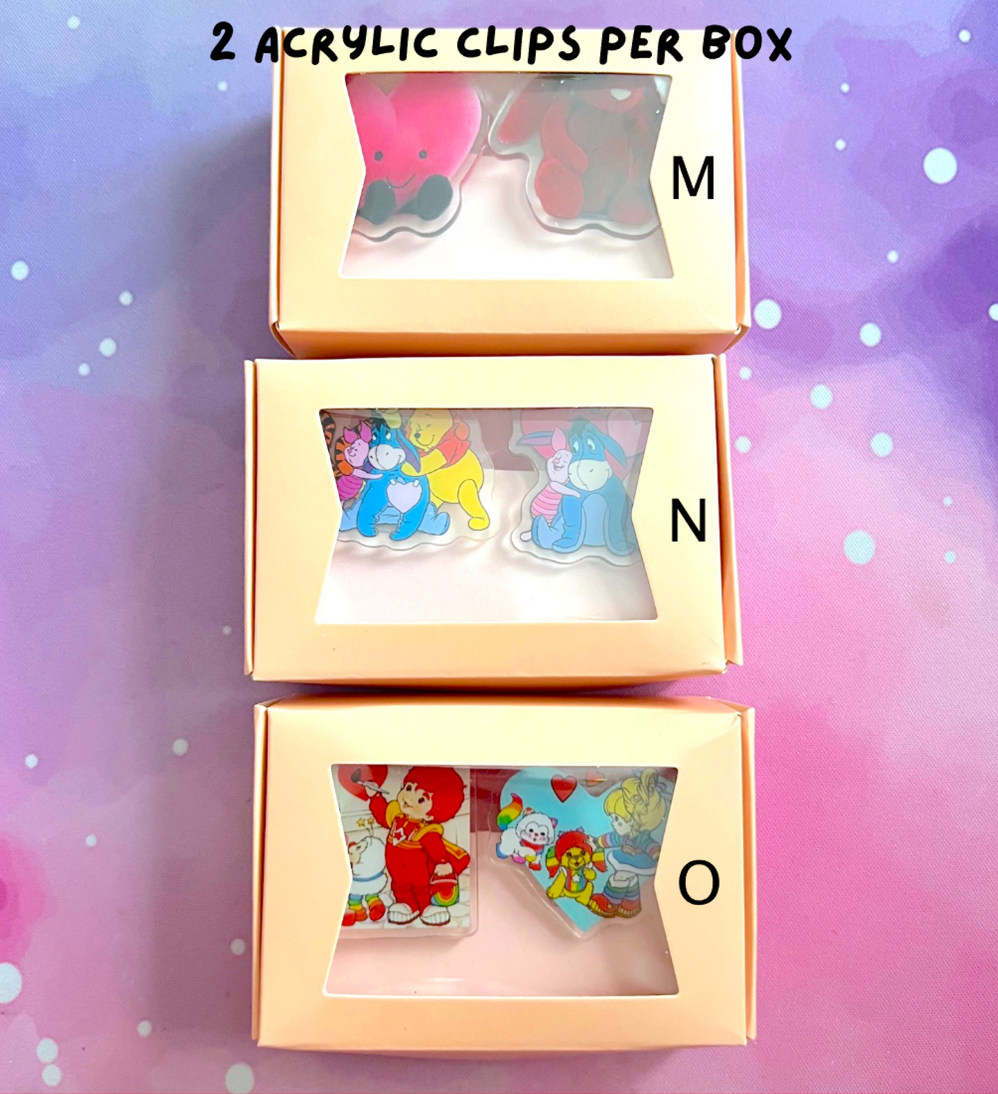 Three boxes containing acrylic clips with colorful designs on a gradient background.
