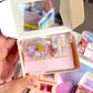 Hand holding a small box with decorative pins and cards.