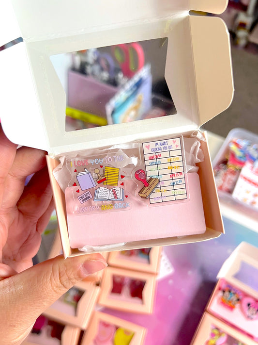 Hand holding a small box with decorative pins and cards.