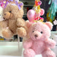Two teddy bear keychains, one pink and one brown, with decorative elements on a blurred background.