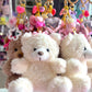 Plush teddy bear keychain with decorative elements on a white surface