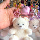 Hand holding a teddy bear keychain with decorative elements on a blurred background
