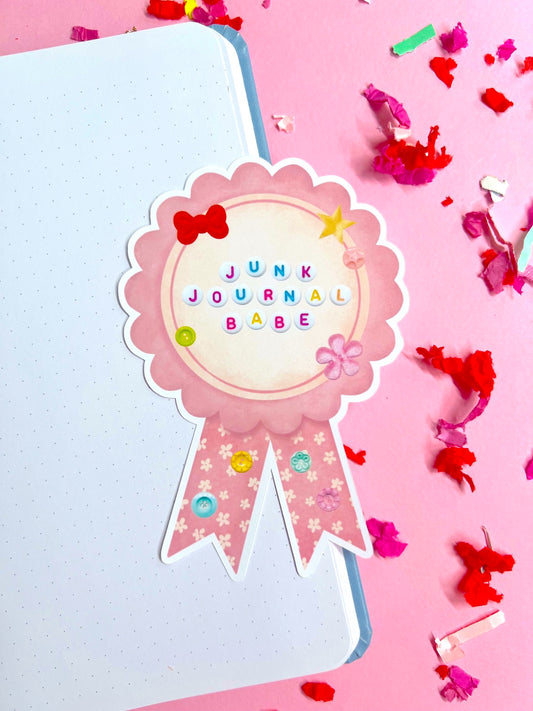 Decorative sticker with 'Junk Journal Babe' text on a pink background with colorful confetti.