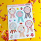 Sheet of decorative stickers with ribbons and text on a yellow background with confetti.