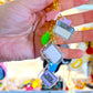 Hand holding a keychain with colorful charms against a blurred background