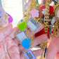 Colorful keychain with various charms held in a hand against a blurred background