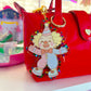 Red handbag with a colorful clown charm on a shelf.