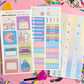 Colorful planner stickers on a pink background with decorative items.