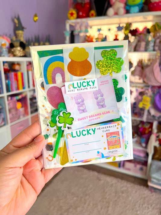 Hand holding a colorful mini scrapbook pack with 'Lucky' theme in a store setting.