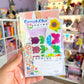 Pack of spring-themed stickers held in front of a colorful shelf.