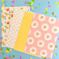 Four sheets of patterned paper on a blue background with colorful flowers.