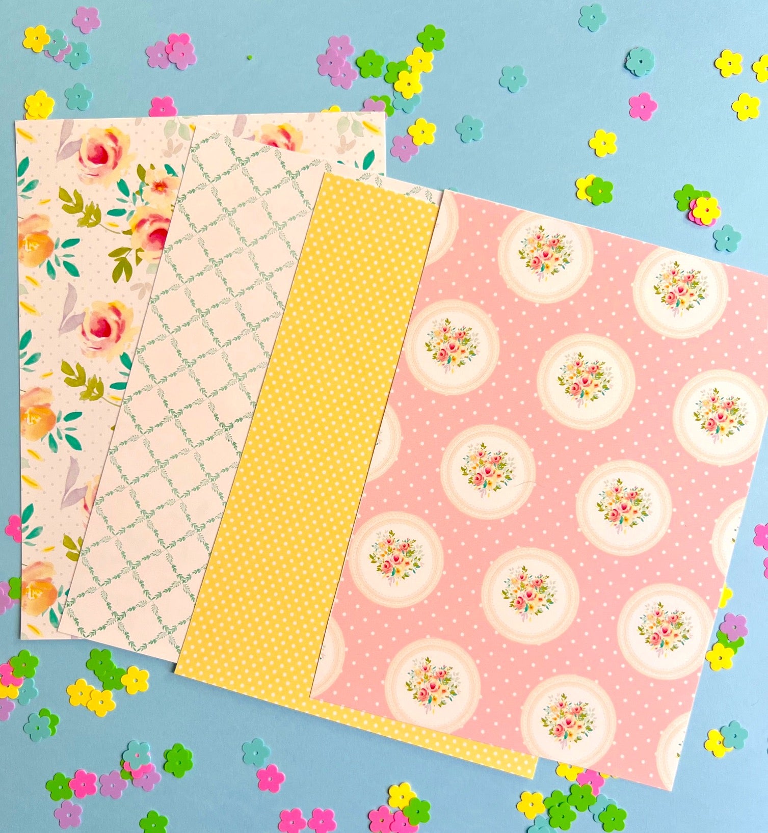 Four sheets of patterned paper on a blue background with colorful flowers.