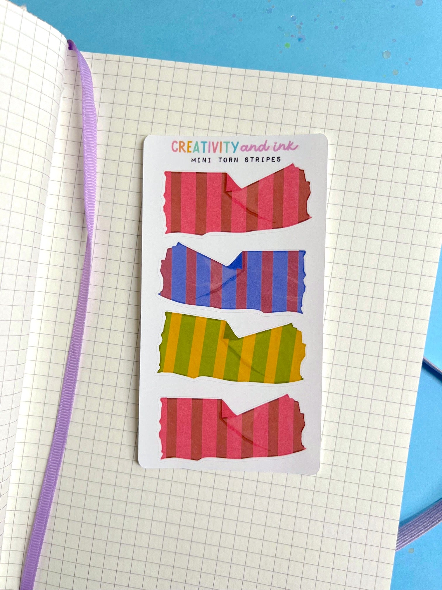 Striped adhesive strips in red, blue, and green on a notebook page 
