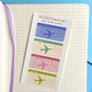 Sheet of mini airplane tickets with colorful designs on a notebook page.