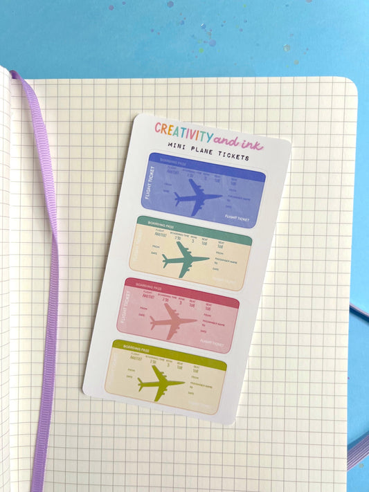 Sheet of mini airplane tickets with colorful designs on a notebook page.