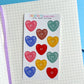 Pack of colorful heart-shaped buttons on a grid notebook page 