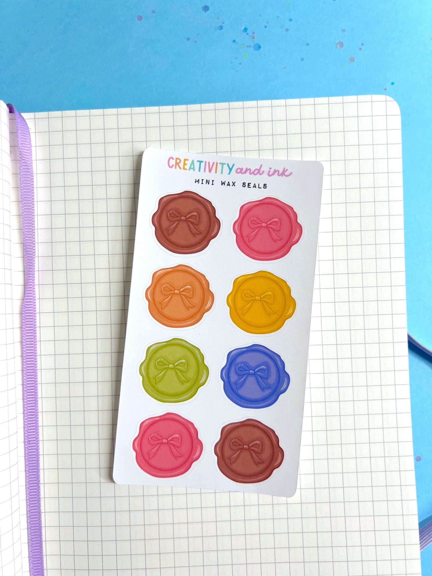 Sheet of colorful wax seal stickers on a notebook with a blue background