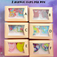 Six boxes containing acrylic clips with colorful designs on a purple background.