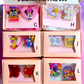 Set of acrylic clips in clear boxes with colorful designs and text.