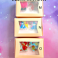 Three boxes containing acrylic clips with colorful designs on a gradient background.